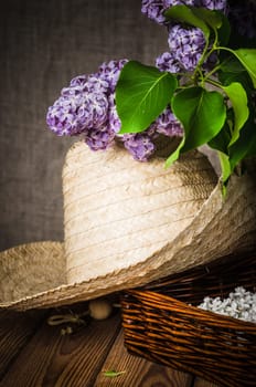 Still-life with a bouquet of lilacs and a straw hat, close-up