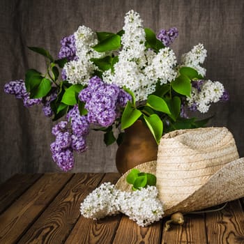 Still-life with a bouquet of lilacs and a straw hat, close-up