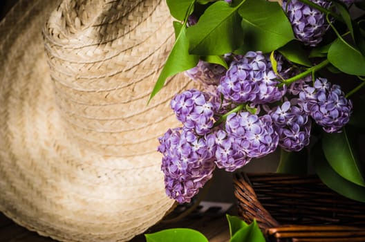 Still-life with a bouquet of lilacs and a straw hat, close-up