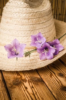 Straw hat and flowering campanula, close-up