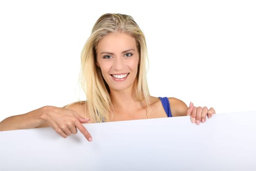 Beautiful young lady pointing to a sign board which she is holding