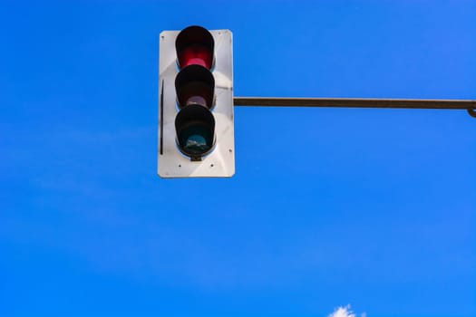 Traffic light and a security camera attached to a pole above the road.