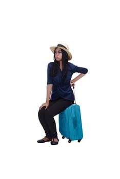 Tired young asian traveler woman sitting on suitcase isolated over white background