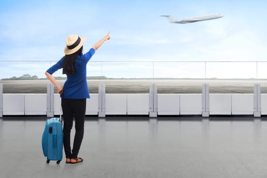 Traveler asian woman carrying suitcase looking airplane at the airport terrace