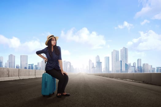 Tired asian traveler woman sitting on luggage waiting flight at terminal airport