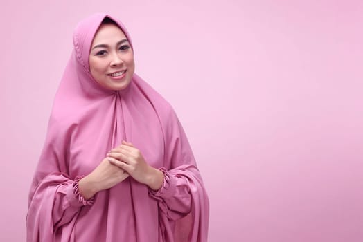 Pretty asian muslim woman wearing hijab dress over pink background
