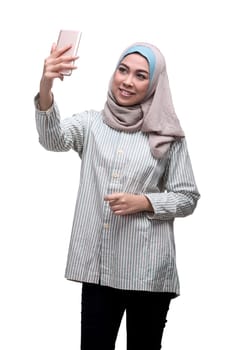 Happy asian muslim woman taking selfie picture with handphone isolated over white background