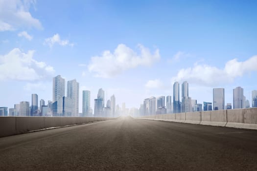 Empty asphalt road and skyscrapers in modern city with blue skyline