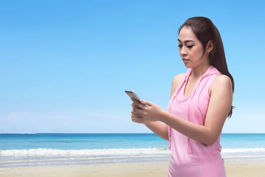 Beautiful asian woman walking while using her phone in the beach