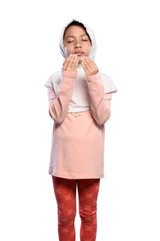 Little asian muslim girl wearing veil praying to god isolated over white background