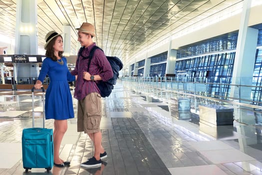 Happy asian couple going vacation with suitcases and bag in the airport
