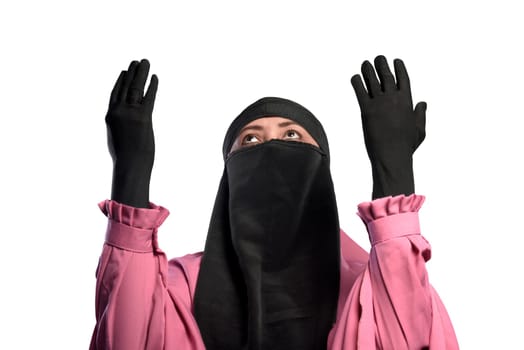 Young asian muslim woman wearing niqab praying to god isolated over white background