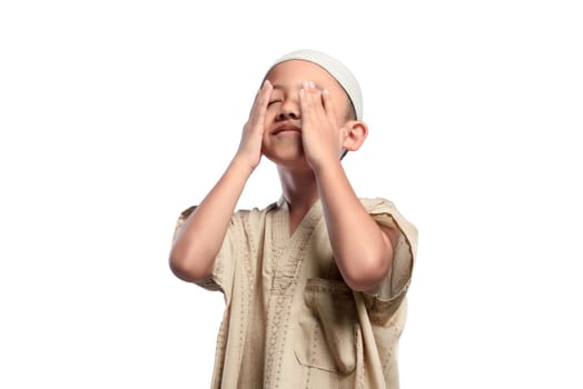 Little asian muslim kid with white cap praying isolated over white background