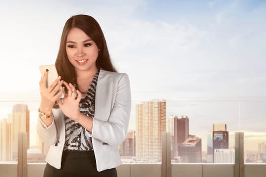 Young asian business woman with a smartphone against cityscape background