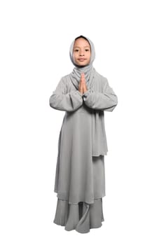 Smiling asian muslim kid with traditional dress standing isolated over white background