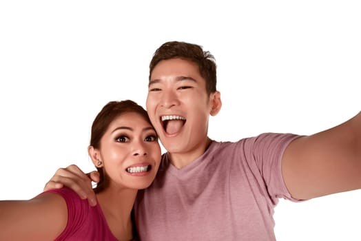 Funny asian couple taking selfie isolated over white background
