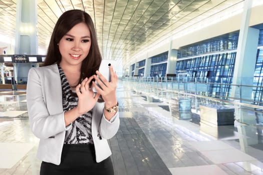 Beautiful asian business woman chatting on her mobile phone while standing in modern building