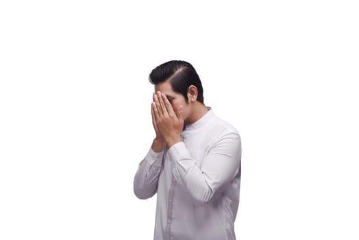 Young asian muslim in traditional dress praying to god isolated over white background