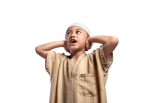 Little asian muslim boy in traditional dress praying isolated over white background