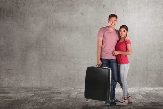 Loving asian couple vacations with luggage bags against grey wall background