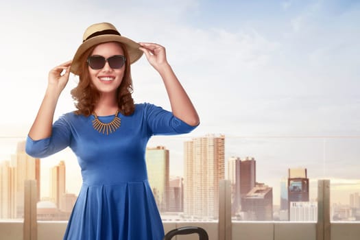 Beautiful asian woman with vintage hat standing in building terrace against skyscraper background