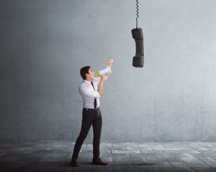 Young asian businessman talking in megaphone to receiver with gray background