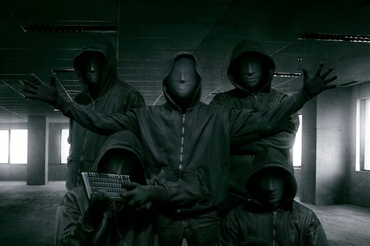 Group of hooded hacker with mask standing in the dark room background