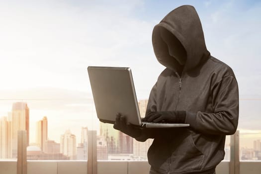 Hacker man with anonymous mask using laptop to hacking in the modern building