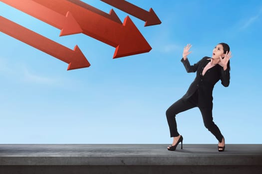 Shocked asian business woman with red arrow going down to her on the sky background