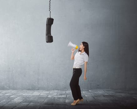 Young asian business woman screaming using a megaphone to black receiver in the city street