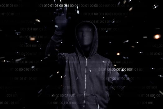 Hooded man with anonymous mask hacking binary system security code on the virtual screen