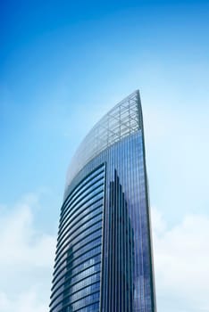 High modern office building with blue glass windows against beautiful sky