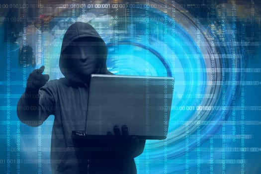 Hooded man with mask holding laptop against binary code in background