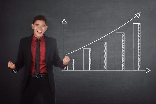 Successful asian businessman standing beside financial graph on the blackboard
