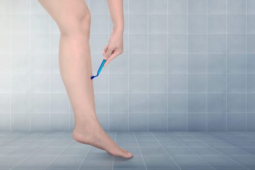 Woman shaving legs with carefully in the bathroom