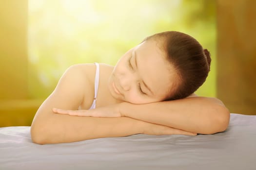 Beautiful asian spa girl lean back on her arm against yellow background