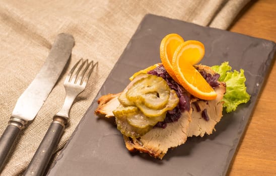 Danish specialties and national dishes, high-quality open sandwich. Roasted Pork belly and Pickled red cabbage and orange served on a plate and ready for eating