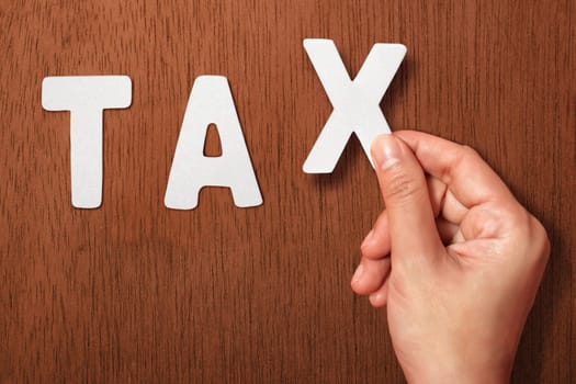 People hand holding Tax alphabet on wooden background