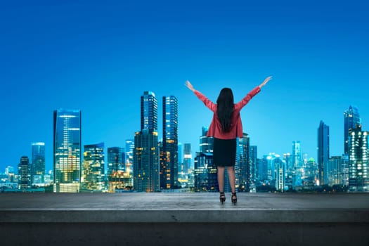 Happy asian business woman standing on a edge a rooftop at night