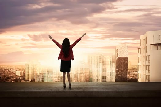 Attractive asian business woman standing on an edge a rooftop looking city view