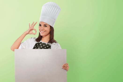 Portrait of asian woman chef showing ok sign with whiteboard for copyspace over green background