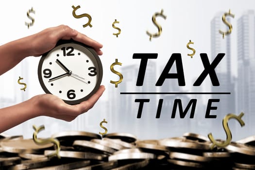 People hand holding alarm clock beside Tax time message on modern background