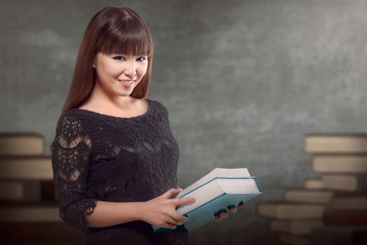 Cheerful asian woman standing and holding a book in the classroom