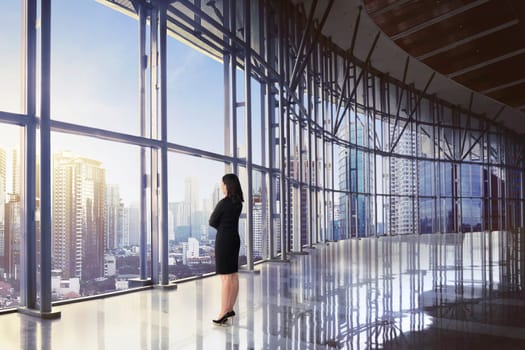 Back view of asian business woman relaxing while looking skyscraper at sunset