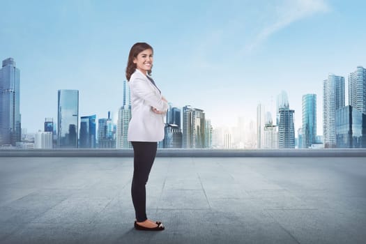 Portrait of a young asian business woman with crossed arm in front of cityscape background
