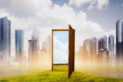 Open wooden door to the new world with green meadow against cityscape background