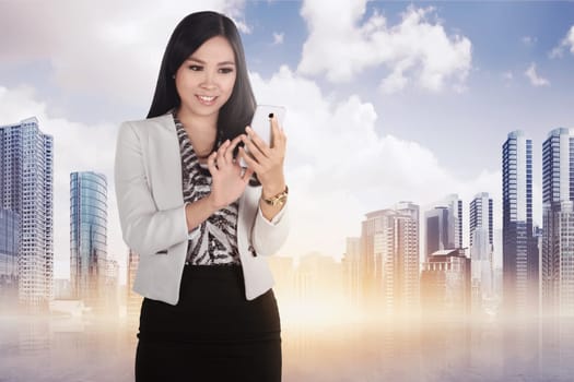 Beautiful asian woman using mobile phone against skyscraper background