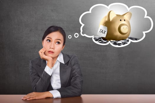 Confused asian business woman thinking her Tax payment with blackboard background