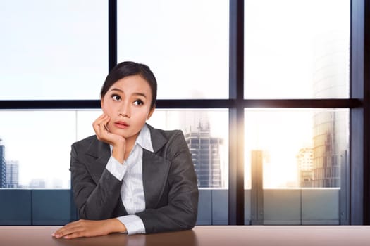 Stressed asian businesswoman thinking the solution while working with glasses window background