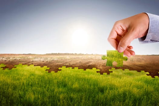 Businessman hand assemble puzzle to build new world with fresh environment. Climate change concept.